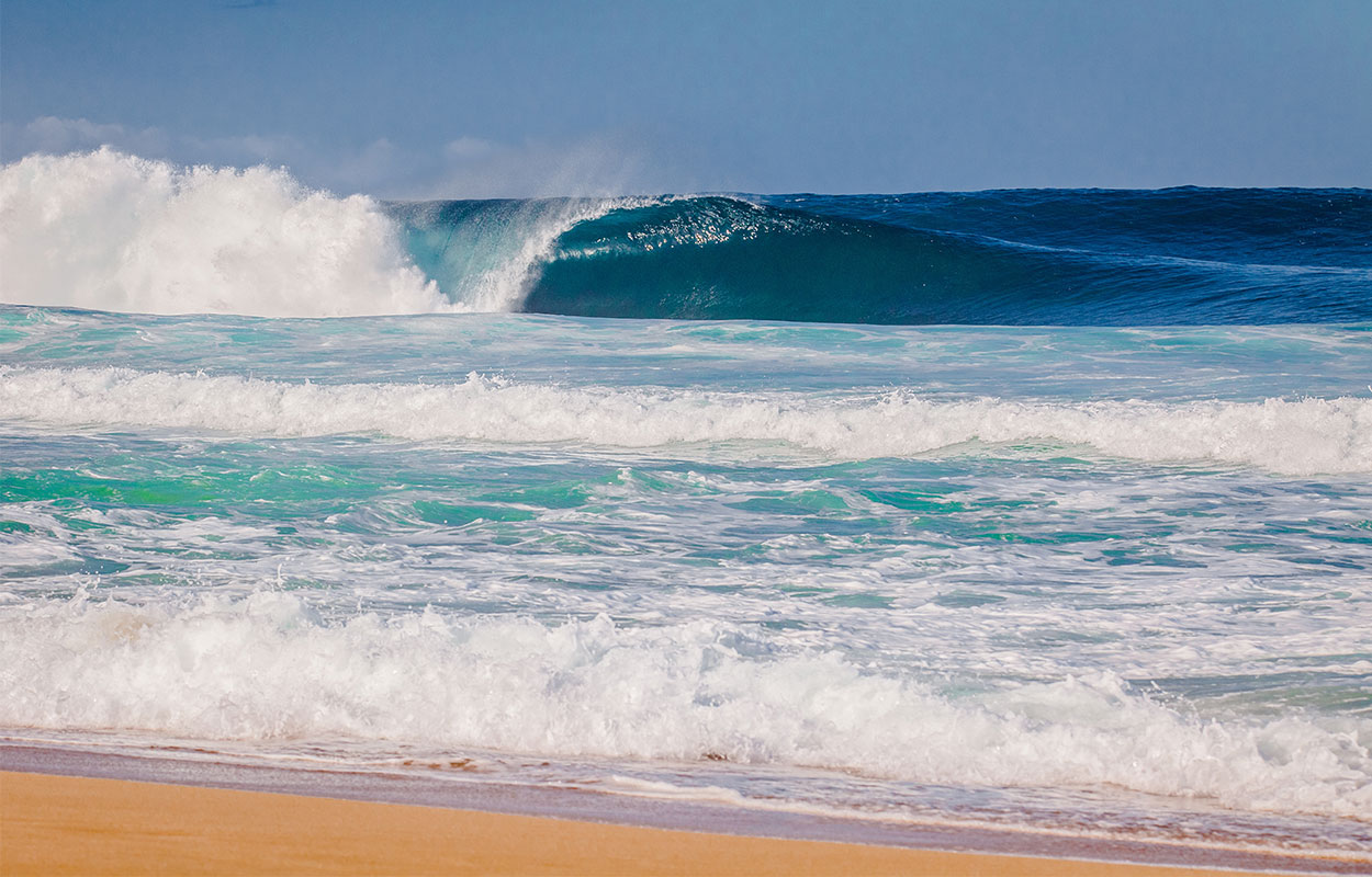 Clear beach day view of Maui shoreline wave break with perfect barrel.